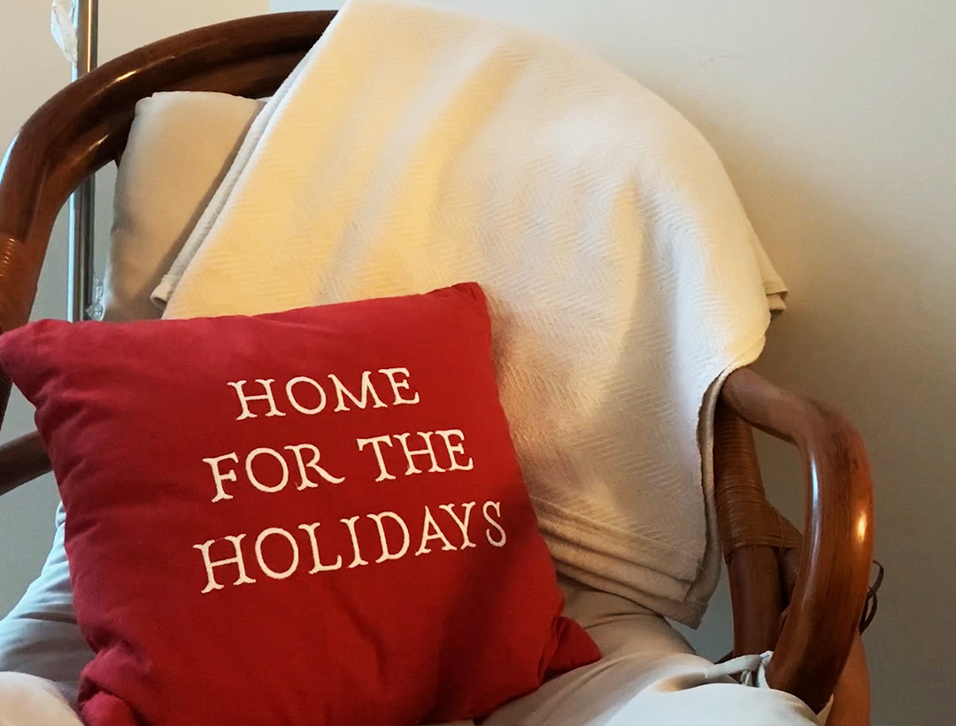 A pillow with "Home for the Holidays" written on it sitting on a chair