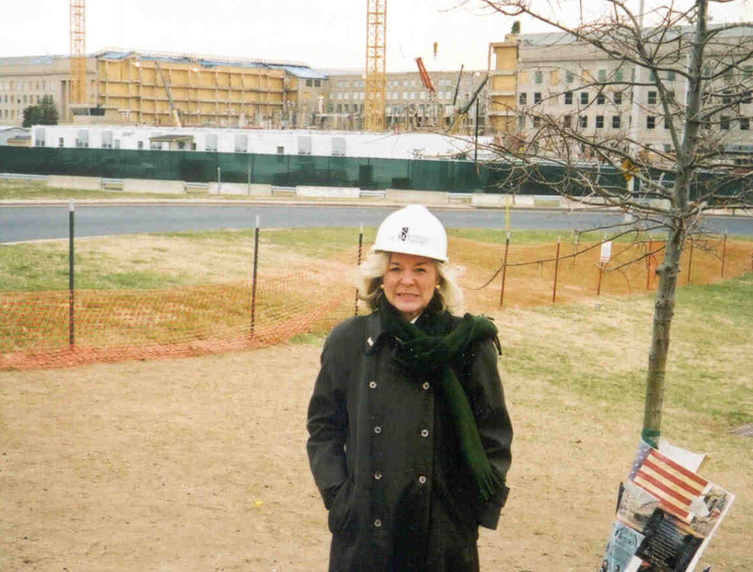 Patty Johnson standing in a white Rebuilding Together hard hat in front of the Pentagon.
